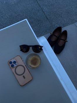 A flat lay image of sunglasses, coffee, and shoes on a chair, perfect for travel themes.