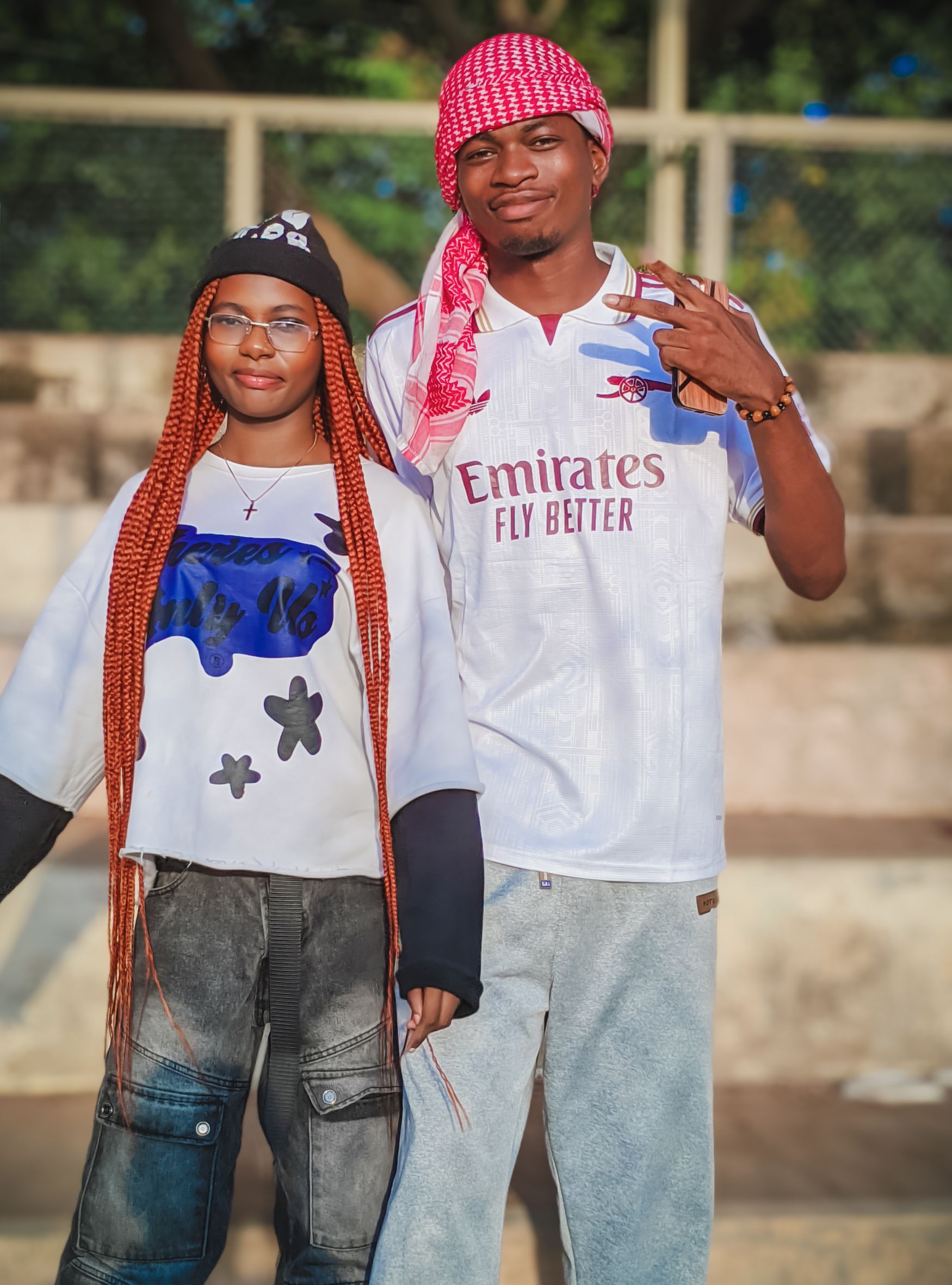 Two stylish young adults pose outdoors in trendy urban fashion, expressing individuality.