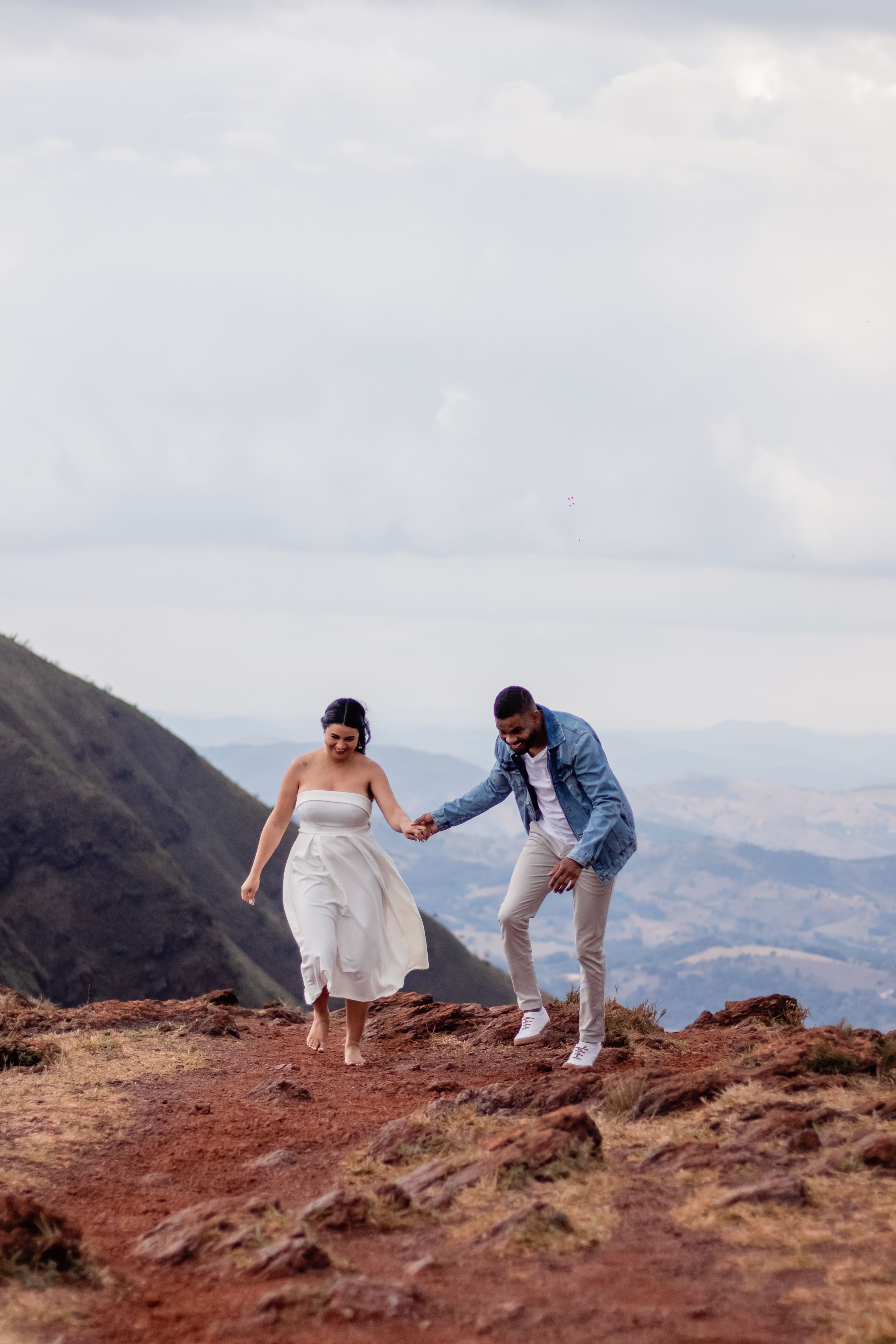 A couple enjoys a romantic walk along a mountainous trail, capturing a joyful moment.