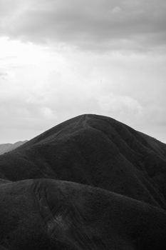 Monochrome image capturing the serene beauty of a mountain under cloudy skies.