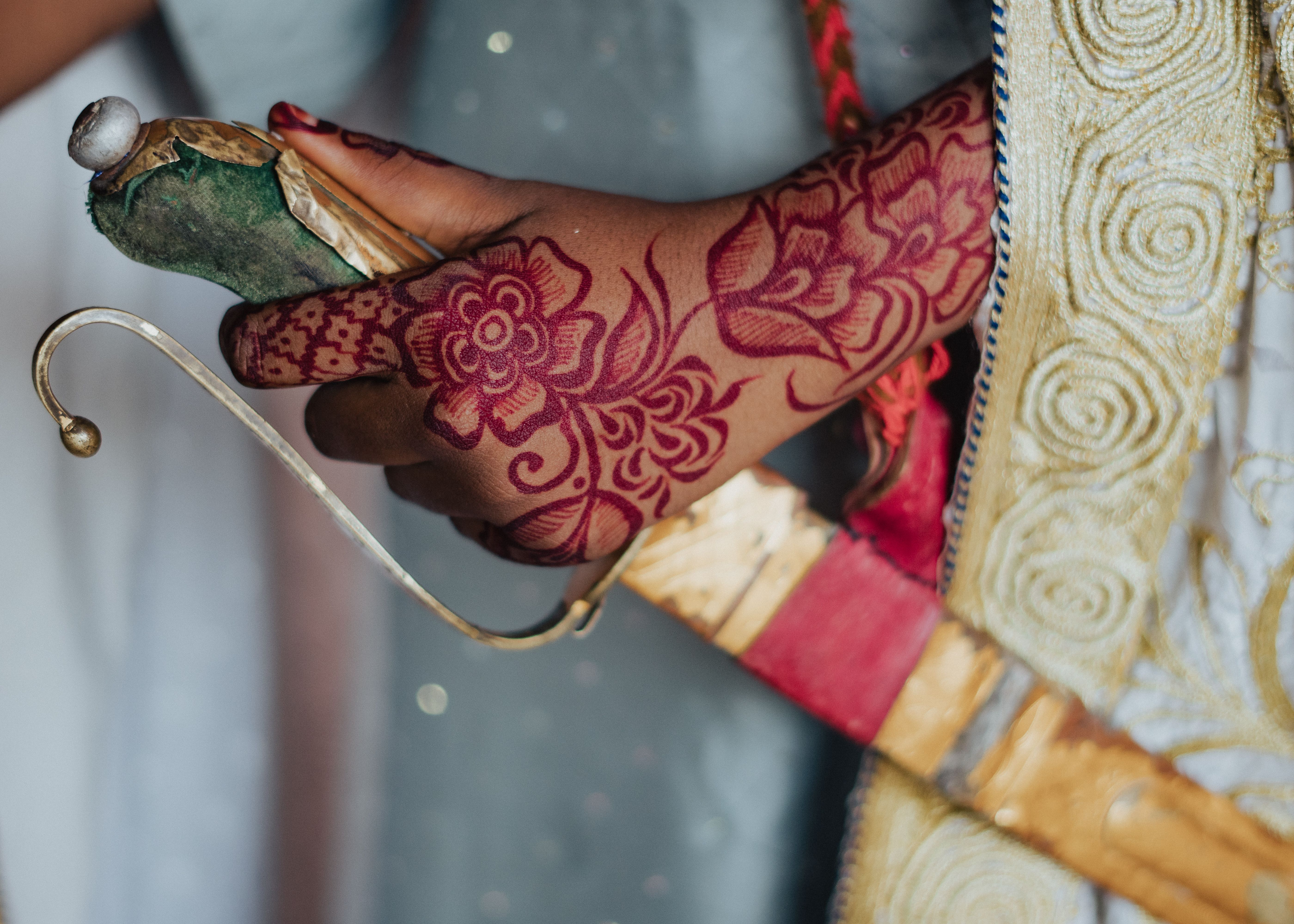 Close-up of intricate henna design on hand holding an ornate sword handle, showcasing cultural elegance.