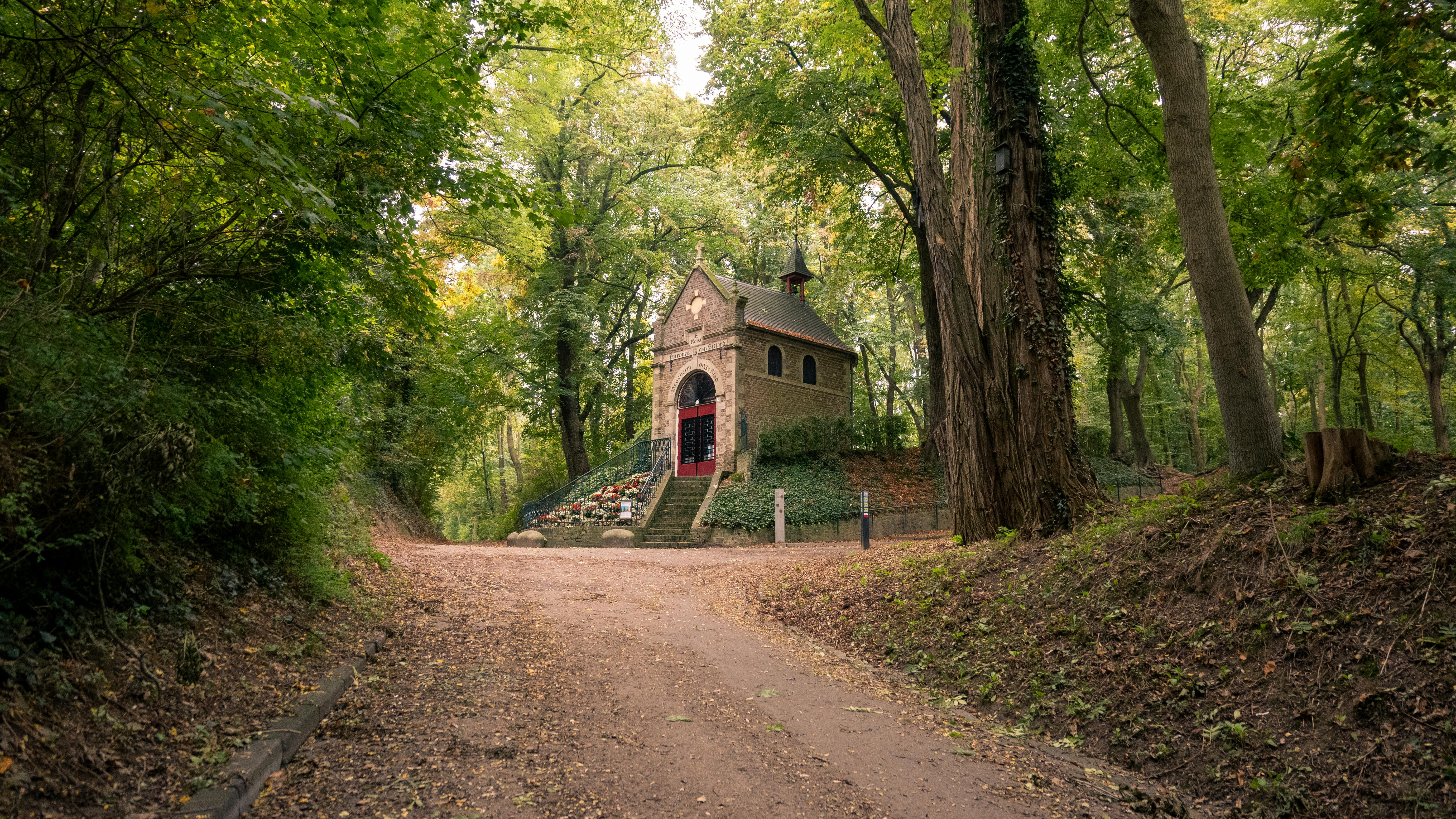 Historic Sint Rosa Chapel in Sittard's lush autumn forest, a serene pilgrimage site.
