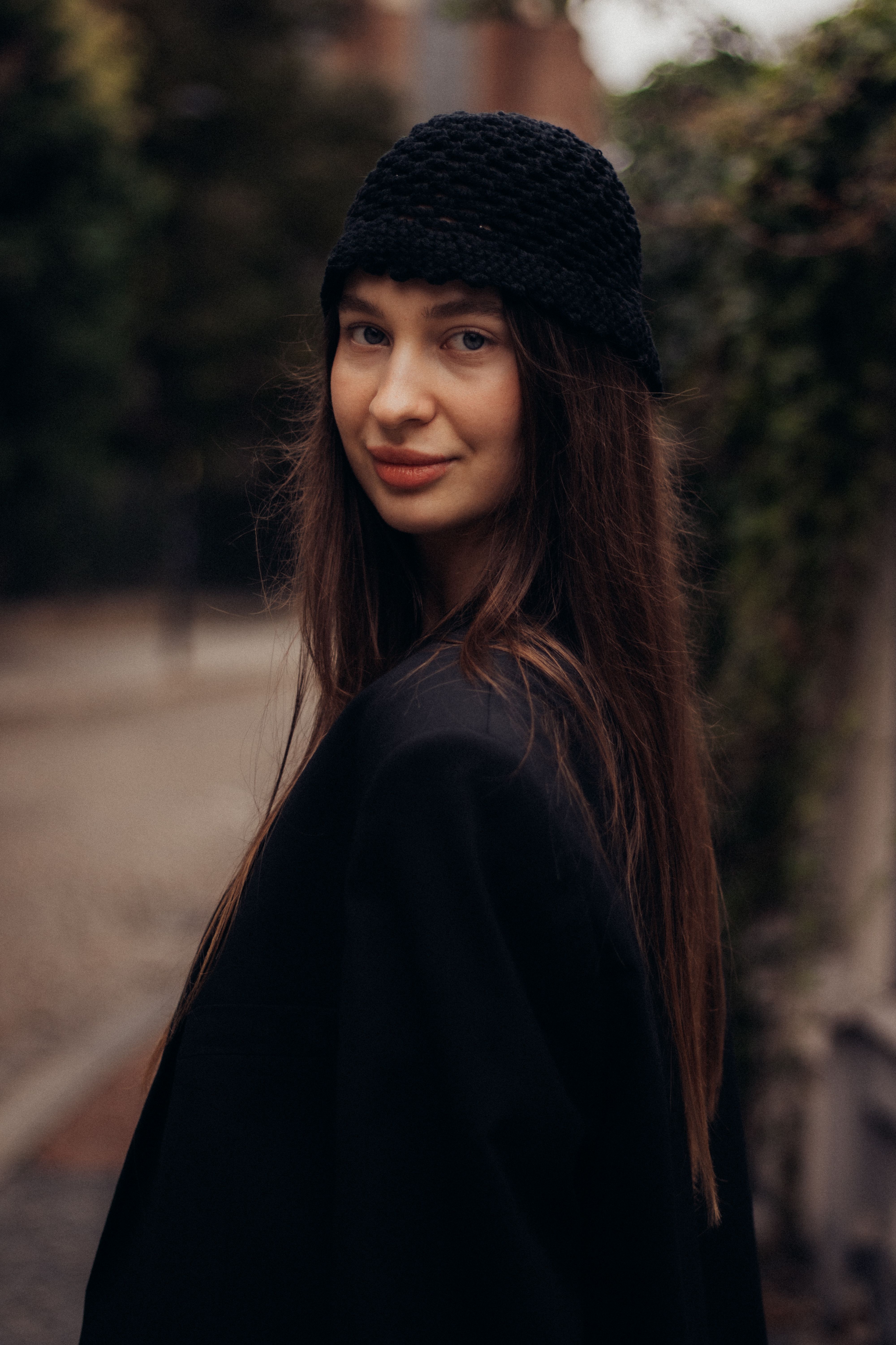 Chic woman wearing a black hat in a moody urban environment. Elegant and stylish portrait.