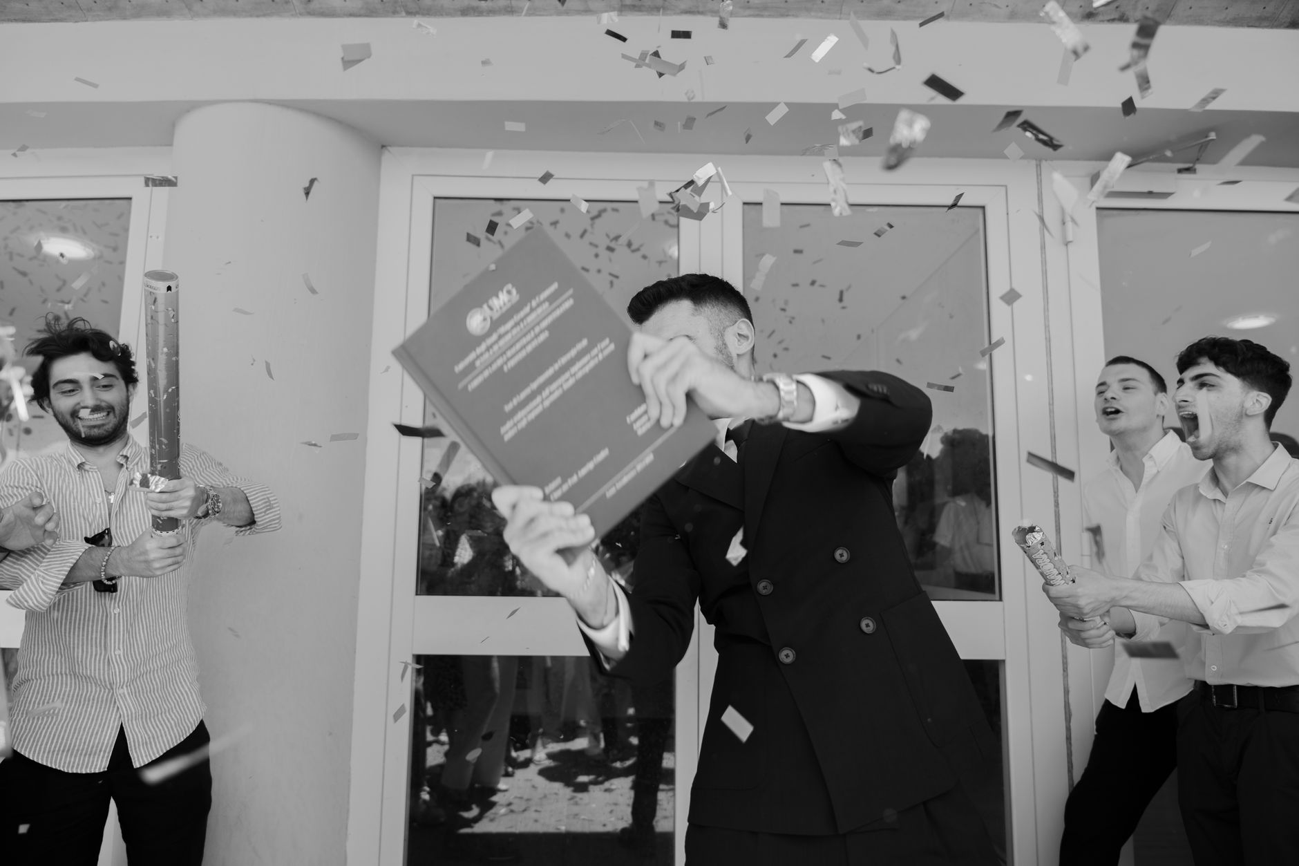 Joyful graduation celebration with confetti and happy graduates in smart attire.