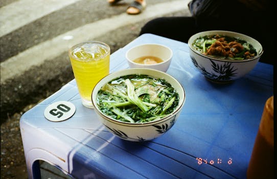 A vibrant street food scene in Hanoi showcasing traditional Vietnamese pho and iced green tea.