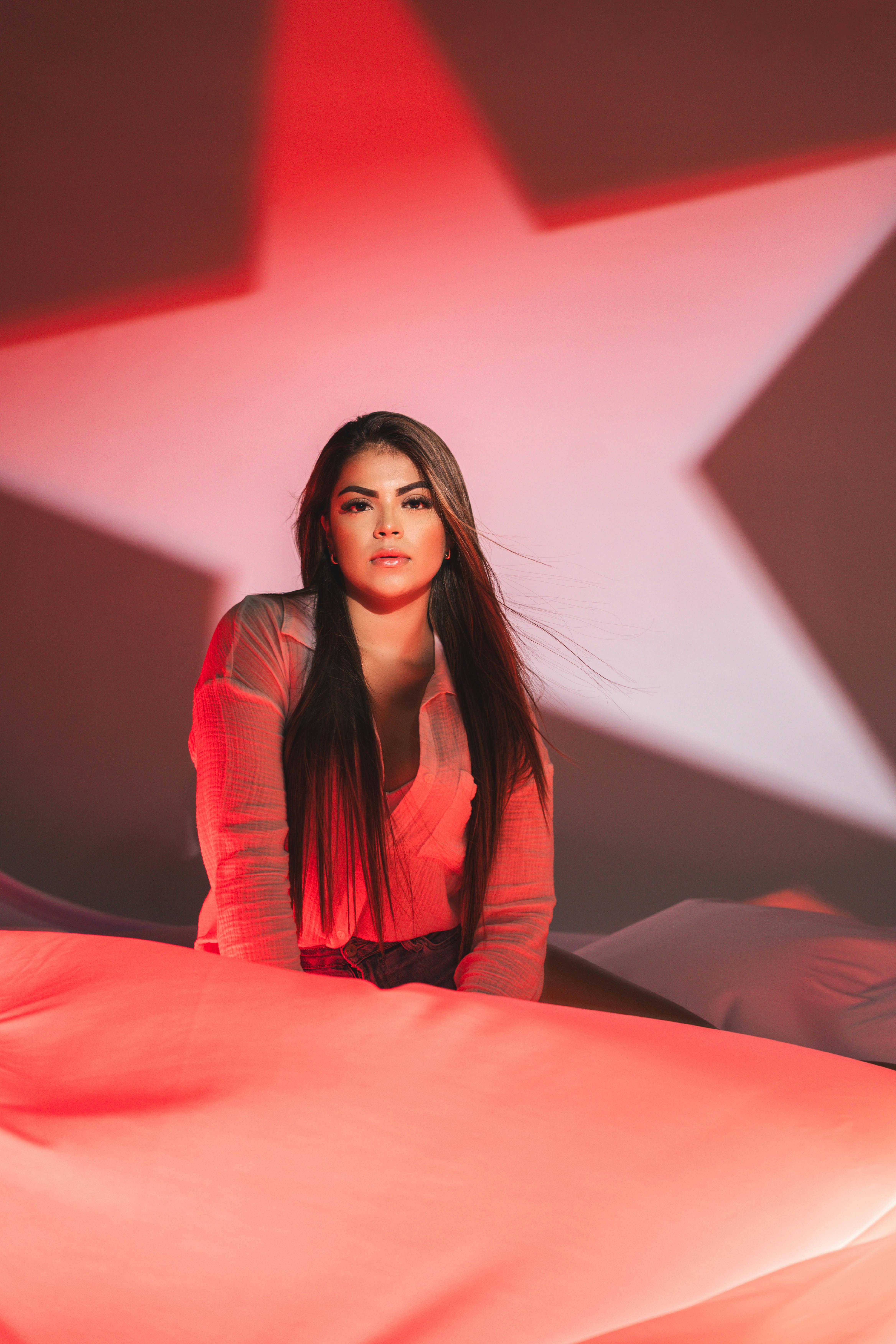 Gratis Affascinante ritratto di una donna illuminato da stelle rosse, che crea un'atmosfera drammatica e artistica. Foto a disposizione