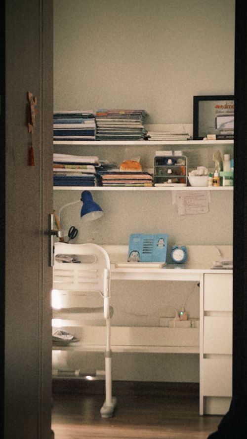 Free A warm, inviting home office space with lamp and organized shelves. Stock Photo