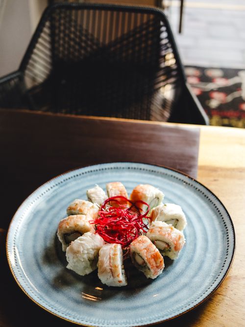 Free A mouthwatering sushi roll artfully presented on a blue ceramic plate in a cozy restaurant setting. Stock Photo