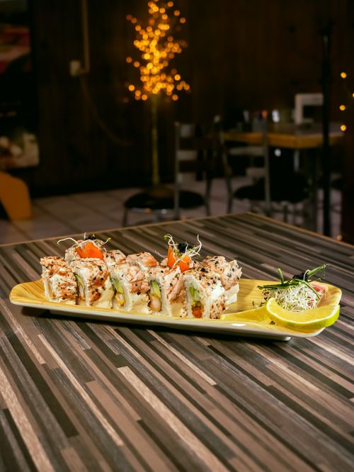 Free Delicious sushi roll elegantly presented on a wooden platter in a cozy restaurant setting. Stock Photo