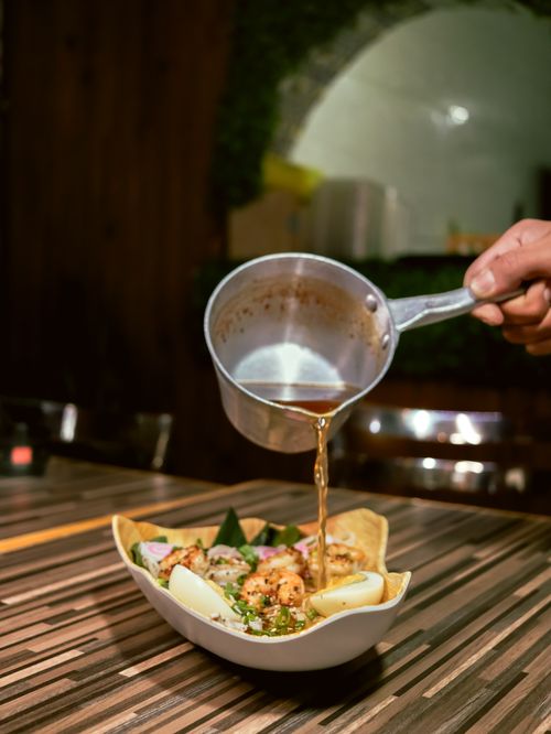 Free A savory soup being poured into a gourmet bowl in a cozy, rustic restaurant setting. Stock Photo