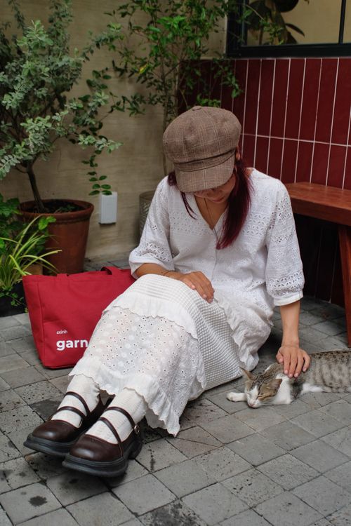 Free Woman in white dress petting a cat outdoors, casual and serene setting. Stock Photo