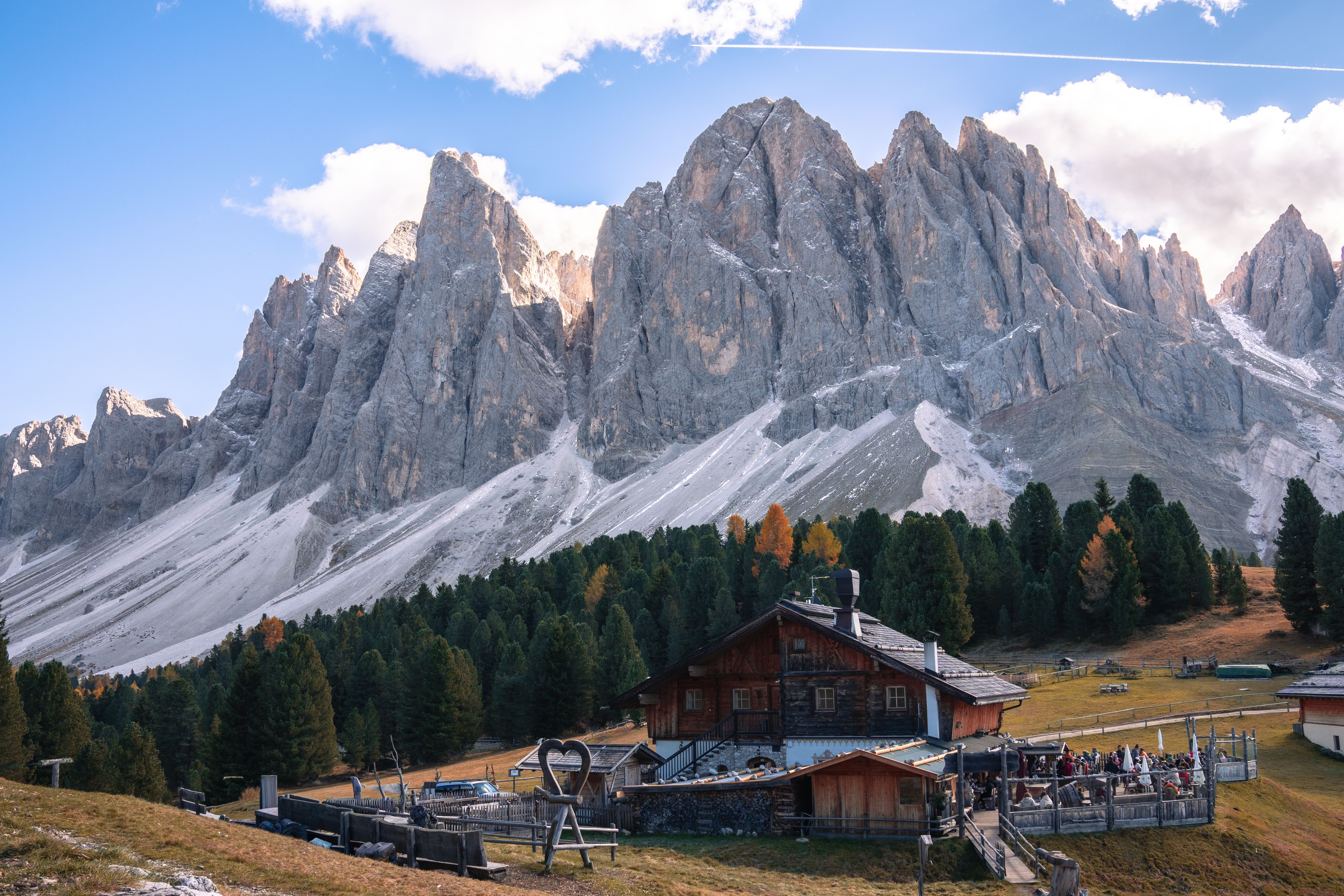 Vue imprenable sur les Dolomites avec un chalet rustique et une forêt en automne en Italie.