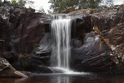 宁静的瀑布在黑暗的岩石地层上流淌，周围是宁静的自然环境