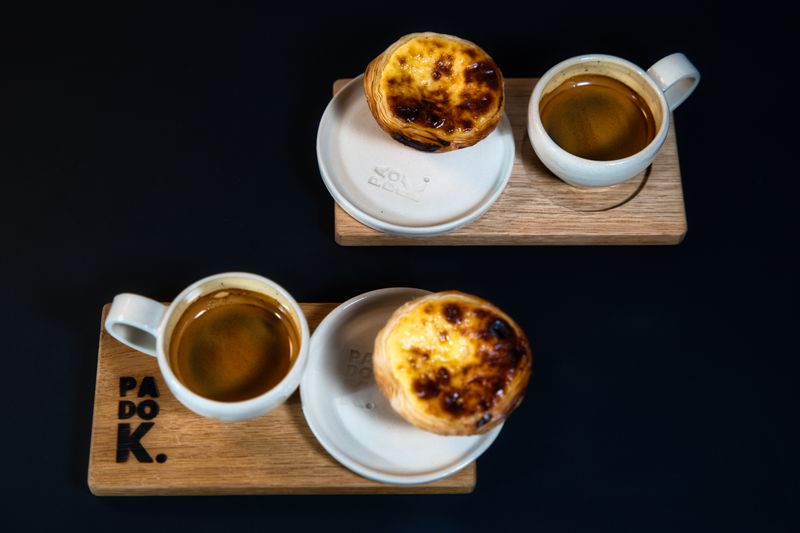 Top-down view of Pastel de Nata and espresso on wooden trays in Berlin, Germany. Ideal for coffee and pastry lovers.