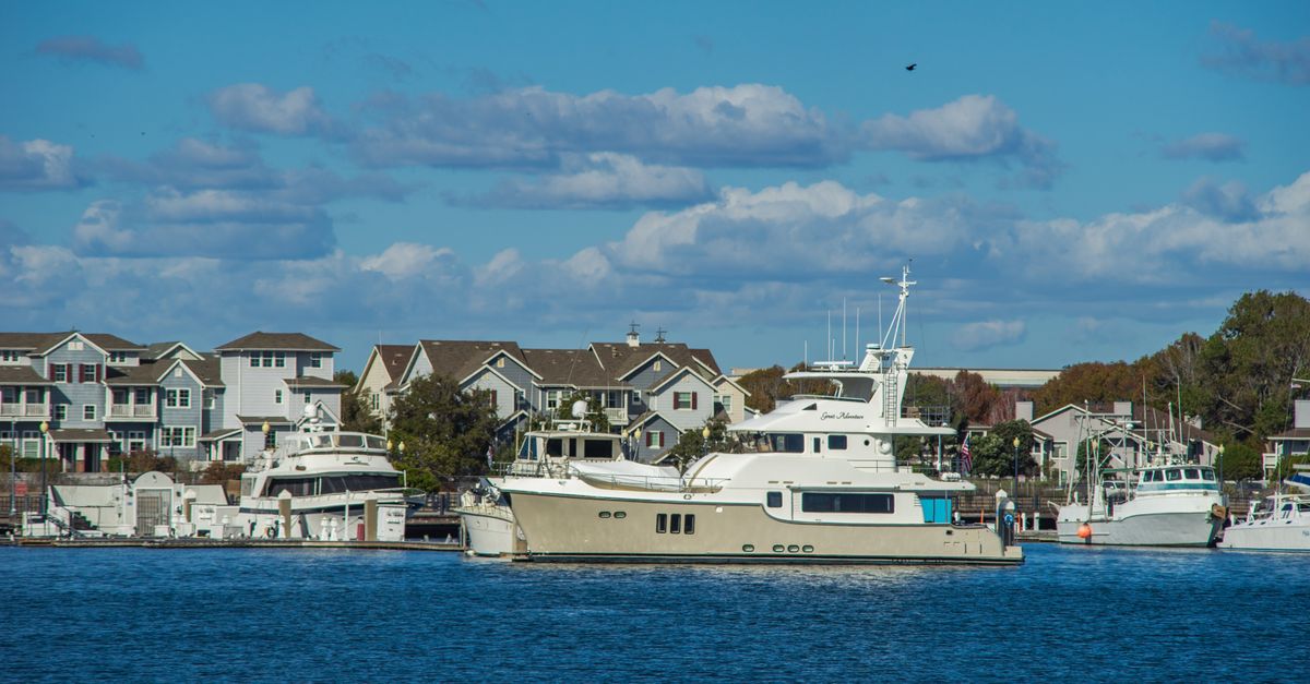Picturesque view of yachts anchored by waterfront houses under a clear blue sky.