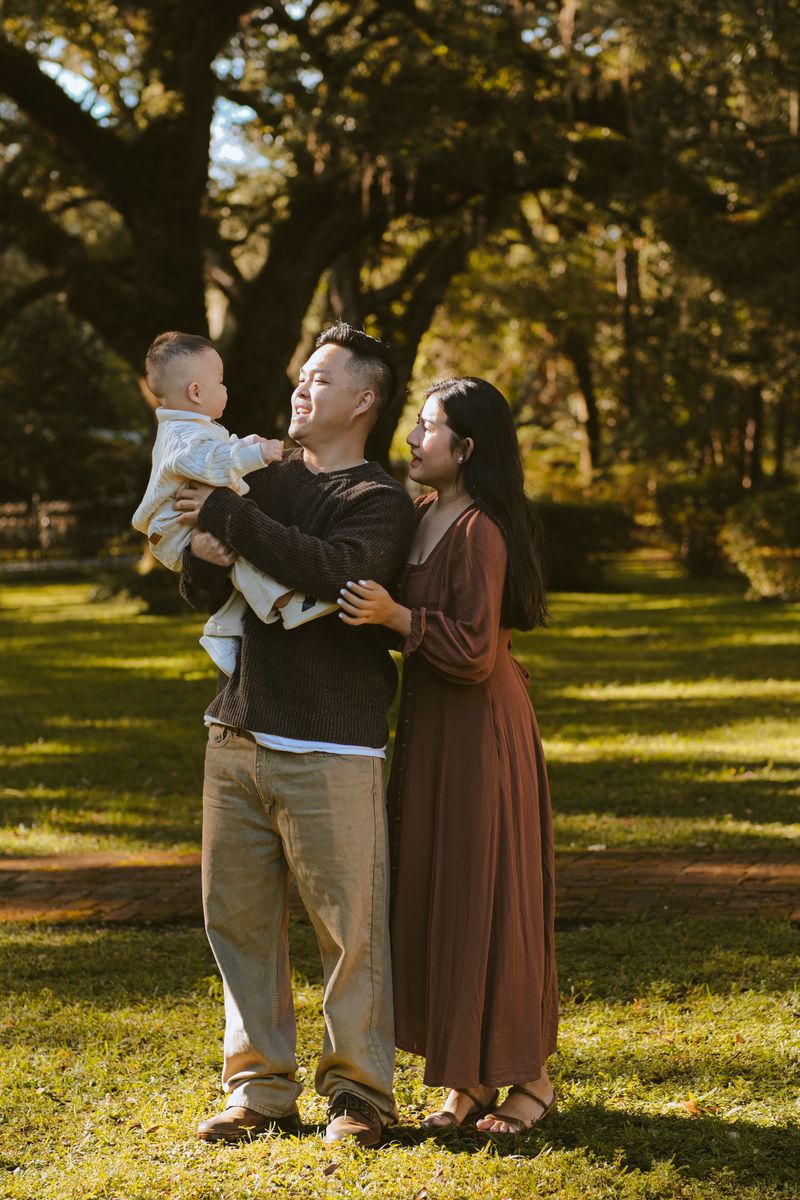 Cheerful family with baby enjoying a sunny day in a lush green park