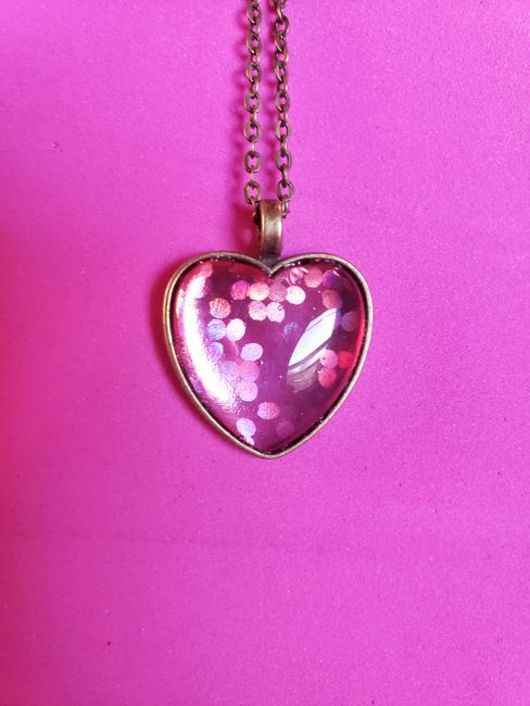 Elegant heart-shaped pendant with confetti design on a vibrant pink background.