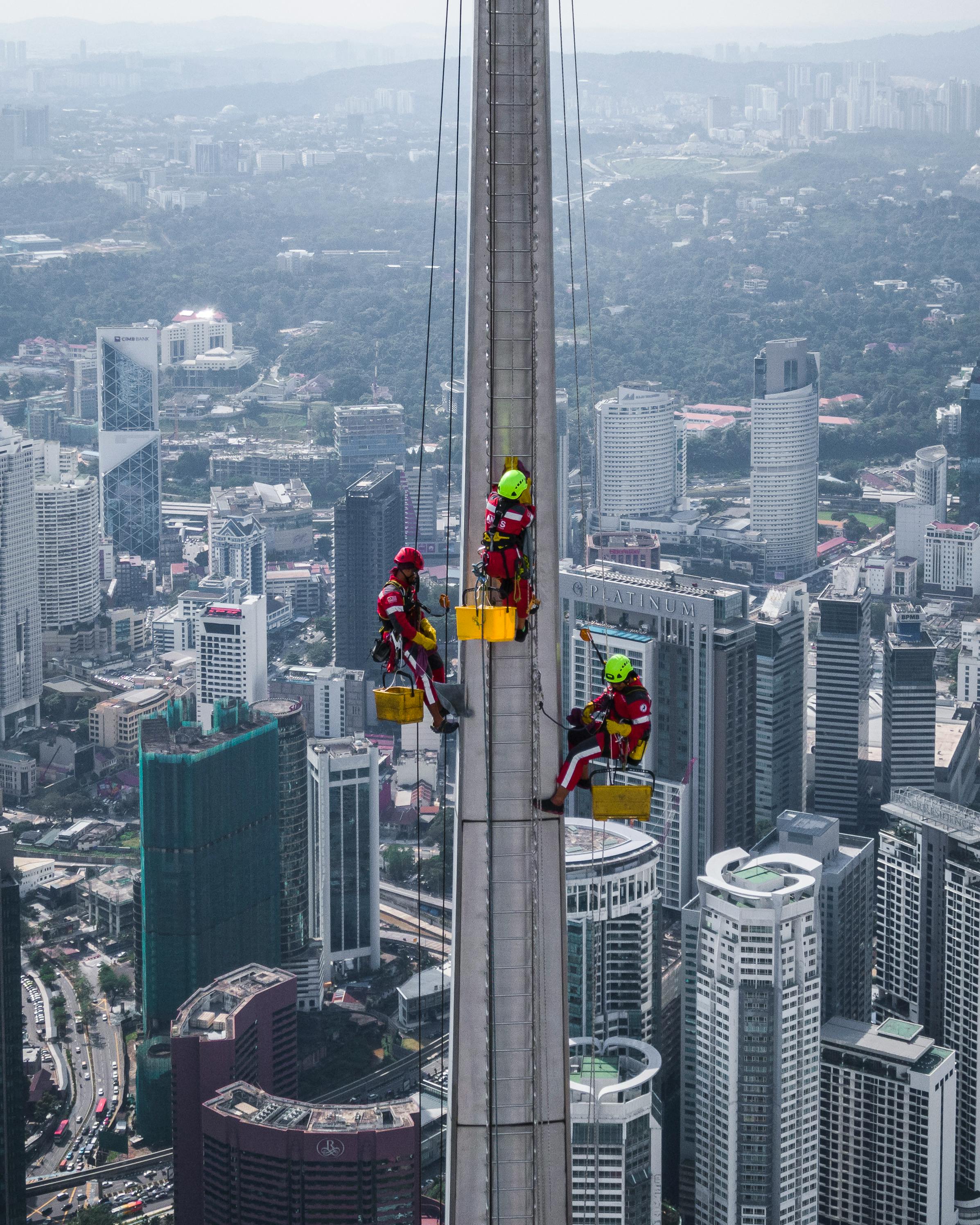 Aerial view of workers cleaning skyscraper windows in Kuala Lumpur, Malaysia.