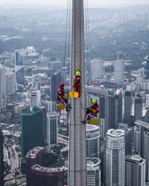 Aerial view of workers cleaning skyscraper windows in Kuala Lumpur, Malaysia.