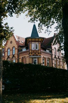 A picturesque Gothic-style brick house surrounded by lush greenery under a sunny sky, capturing architectural elegance.