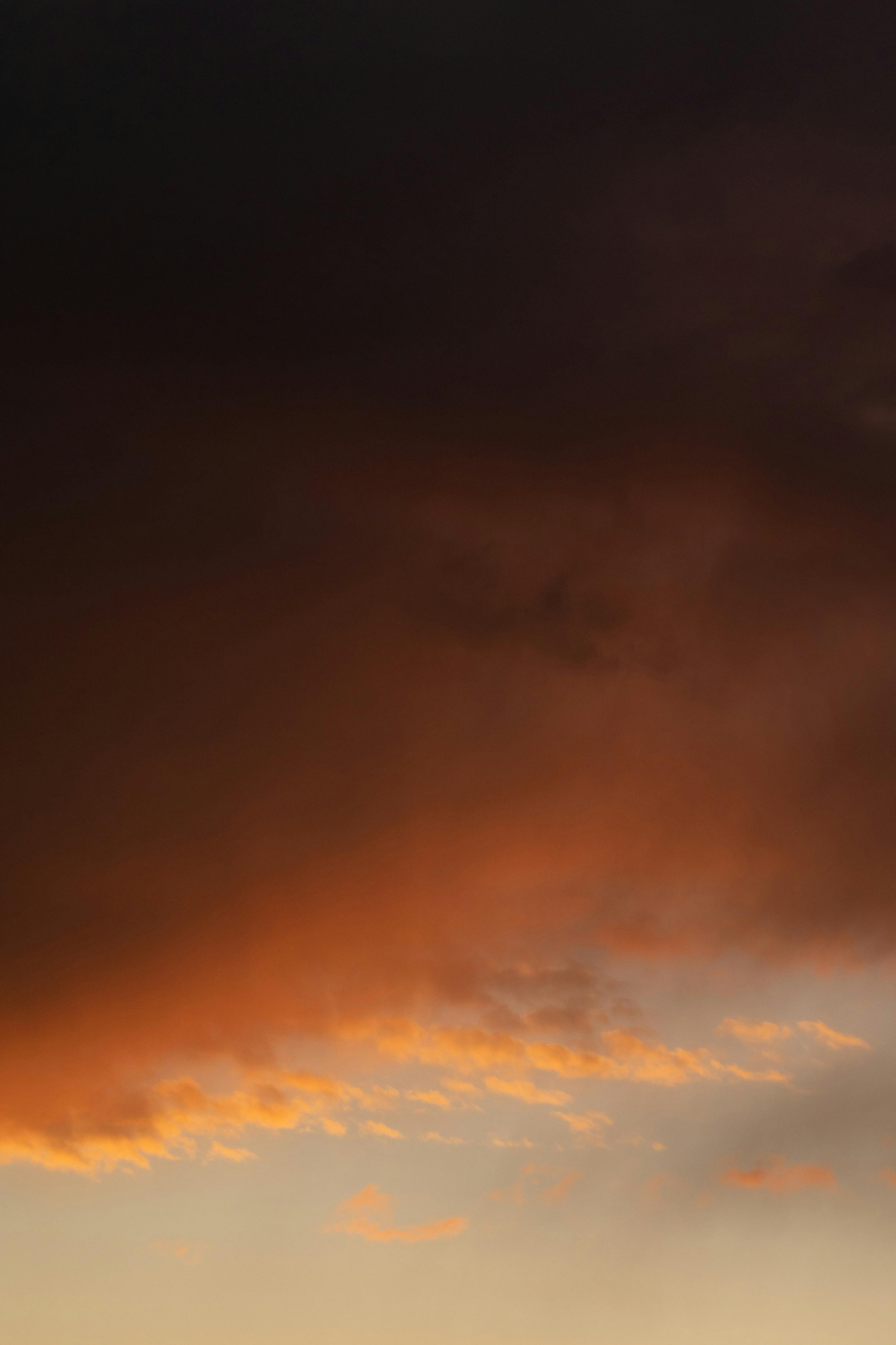 gratis Levendige zonsondergang met dramatische donkere wolken en oranje tinten, perfect voor achtergronden. Stockfoto