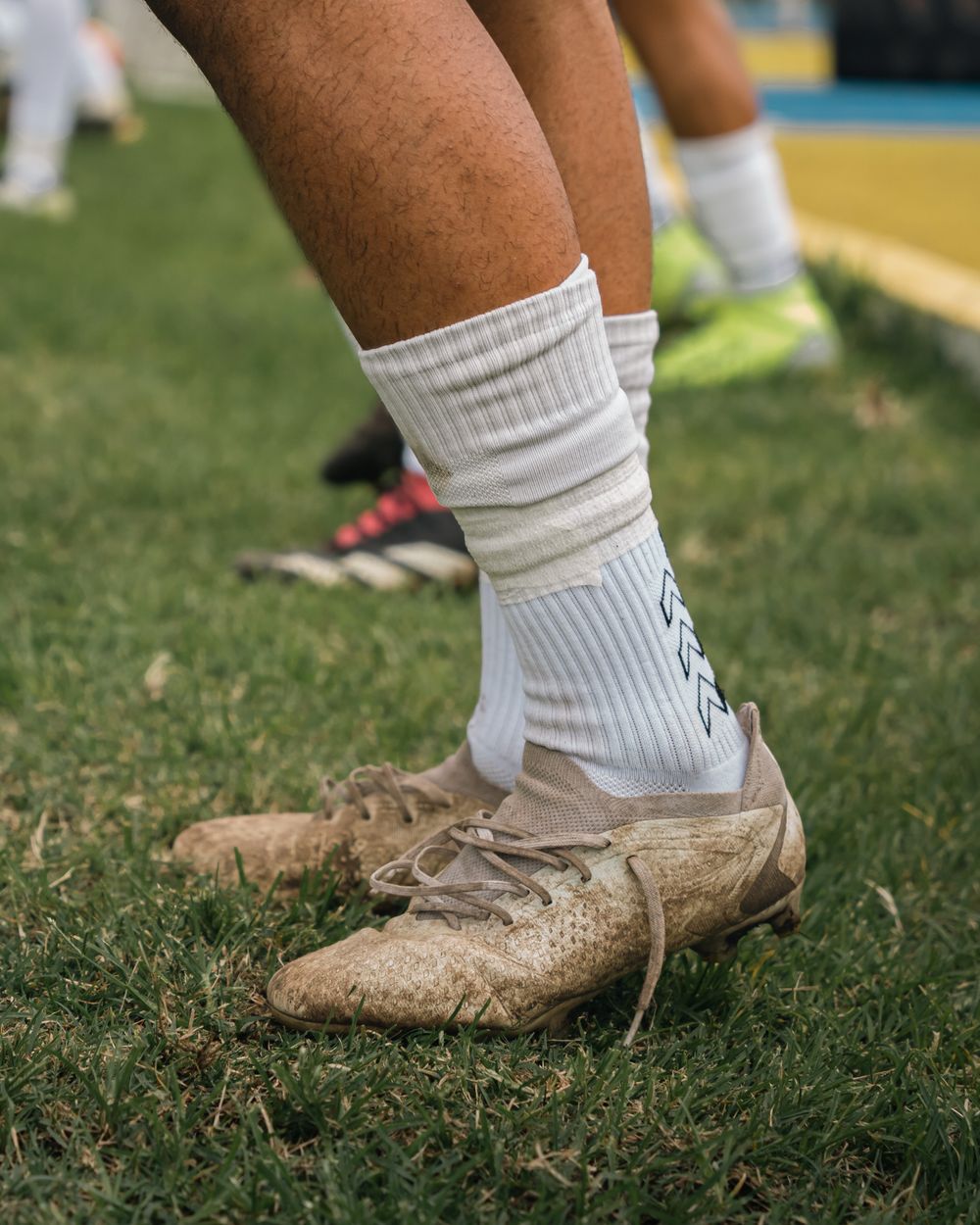 White crew sport socks worn with muddy boots on match grass