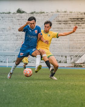Action-packed soccer game with two players contesting for the ball on a bright day.