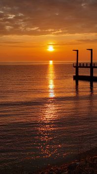 A breathtaking sunset reflection over the tranquil Black Sea with a silhouette jetty.