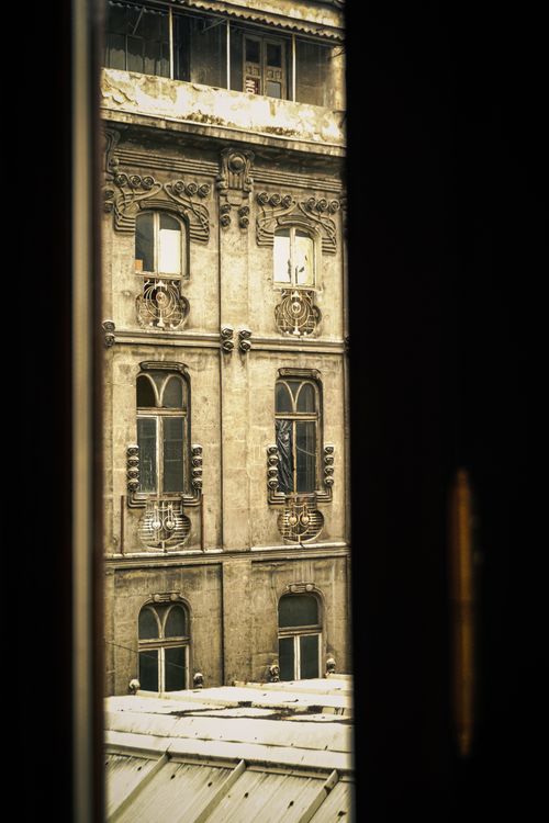 Free View of an ornate historical building facade seen through a window, highlighting classic architecture. Stock Photo