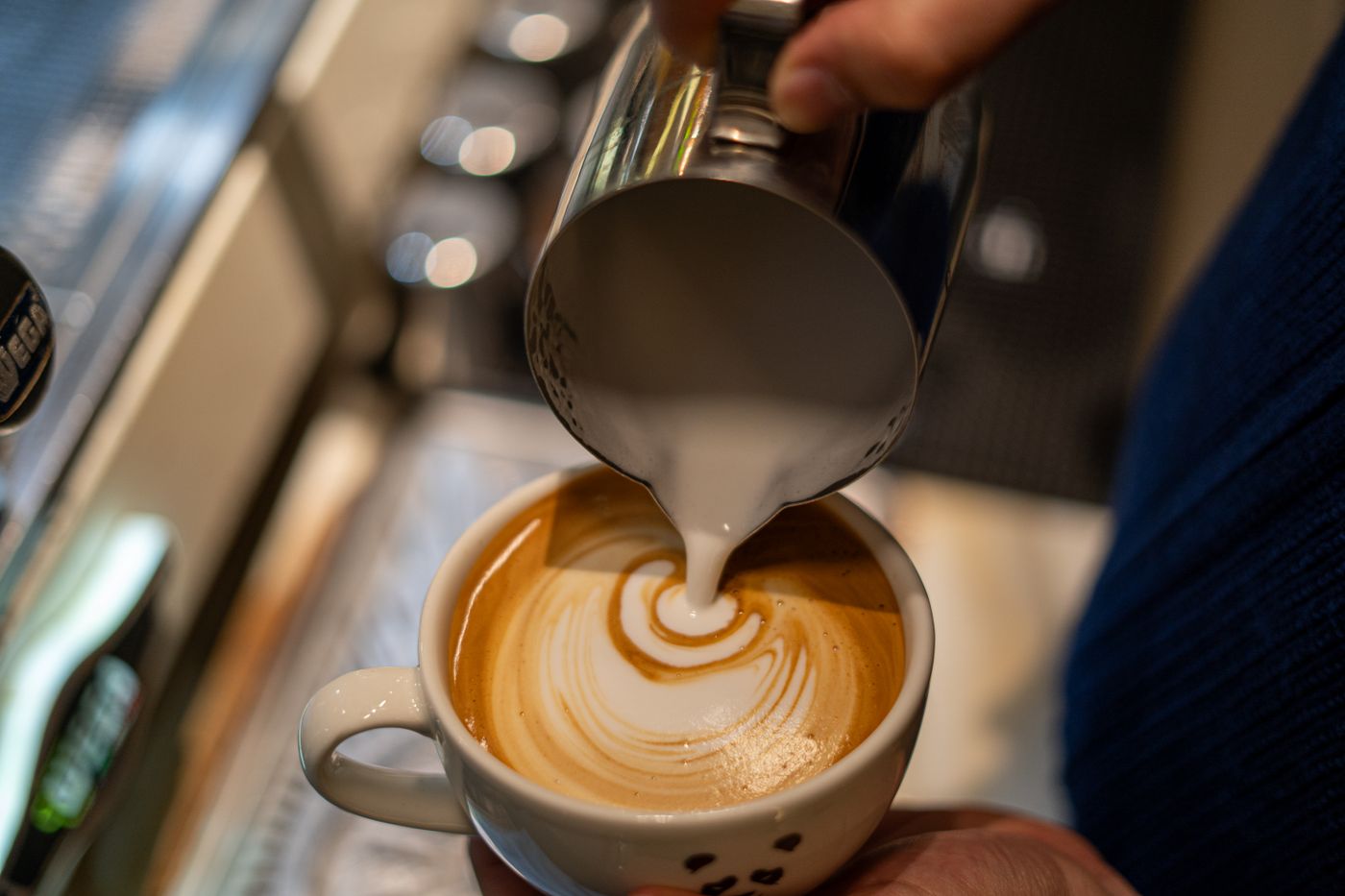 Barista pouring latte art into a fresh coffee