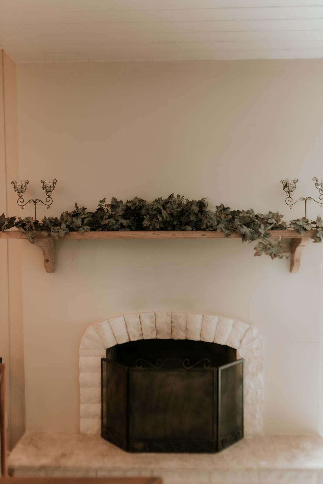 how to style a fireplace mantel: an elegant fireplace styled with greenery and candleholders