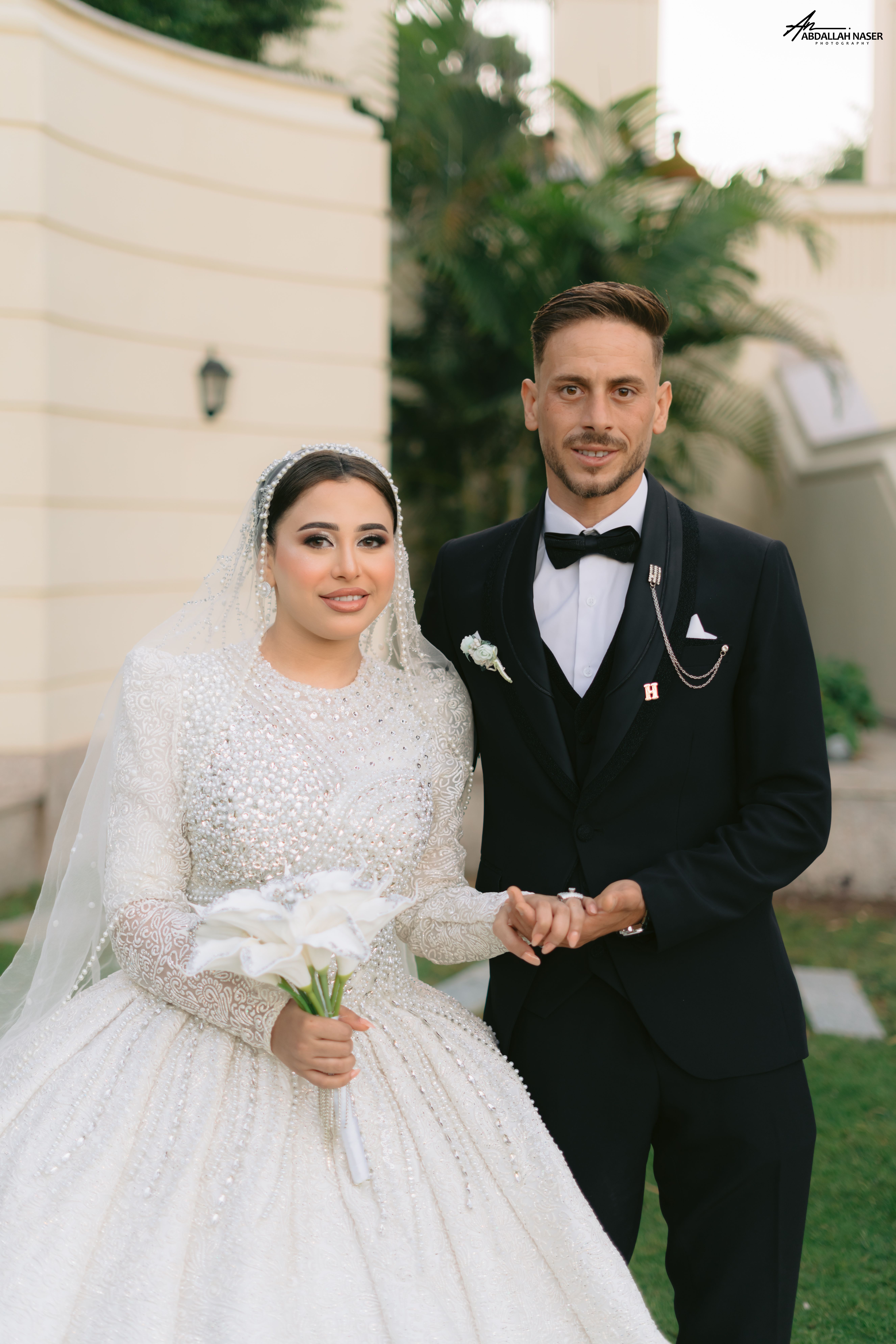 Elegant portrait of a bride and groom in a garden setting, showcasing timeless wedding attire.