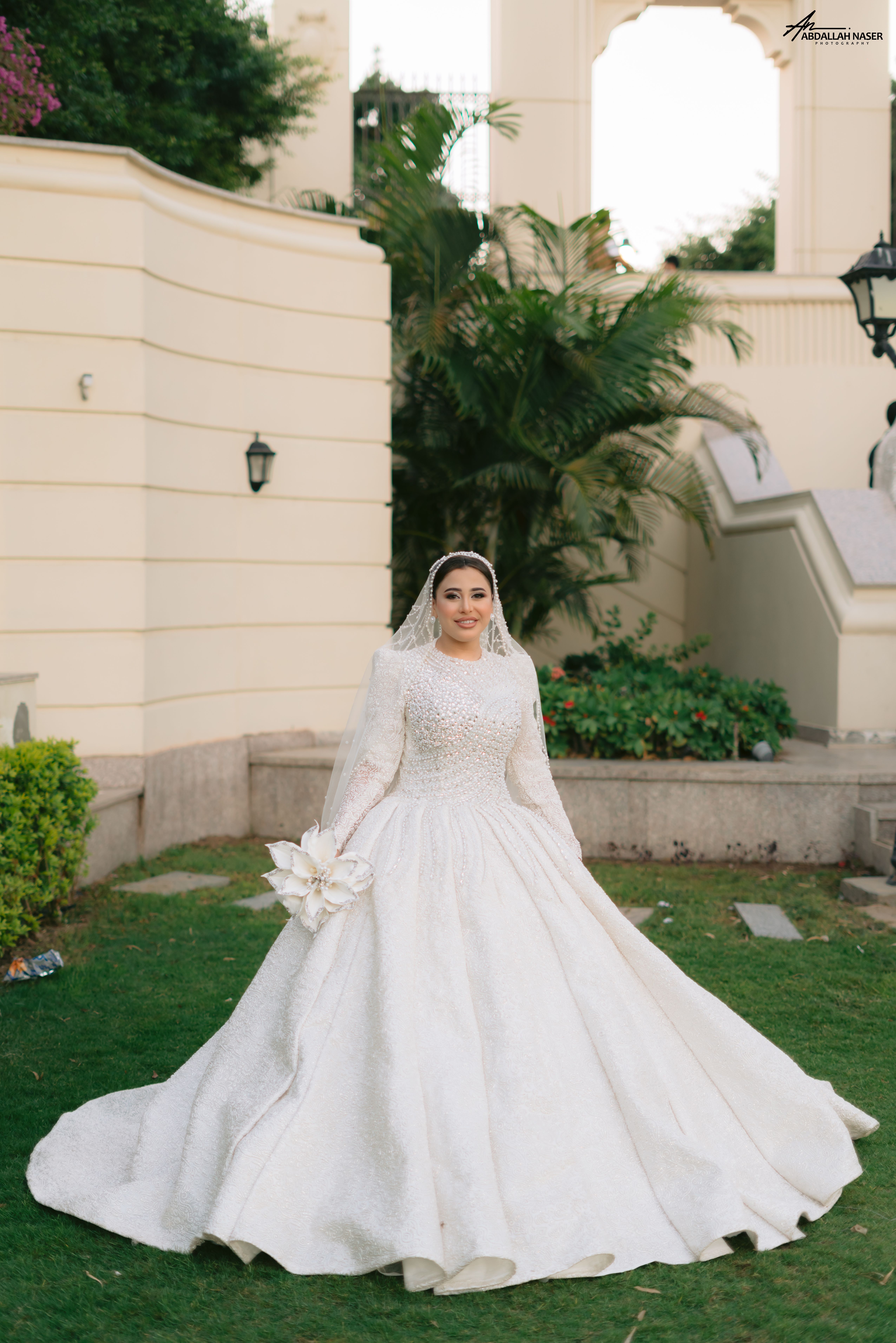 Beautiful bride in white wedding dress with lush garden backdrop.