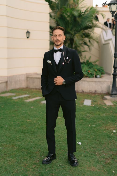 Free A man wearing a black tuxedo stands elegantly in a garden setting, exuding sophistication. Stock Photo