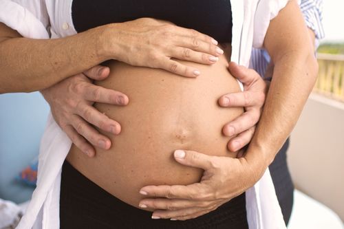 Free A couple lovingly embraces a pregnant belly outdoors symbolizing love and family. Stock Photo