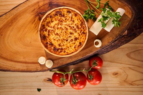 Free Mouthwatering cheese quiche on wooden board with tomatoes and parsley garnish, perfect for culinary themes. Stock Photo