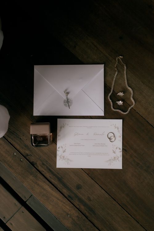 Free Flat lay of wedding invitation, perfume, jewelry, and envelope on wooden surface. Stock Photo