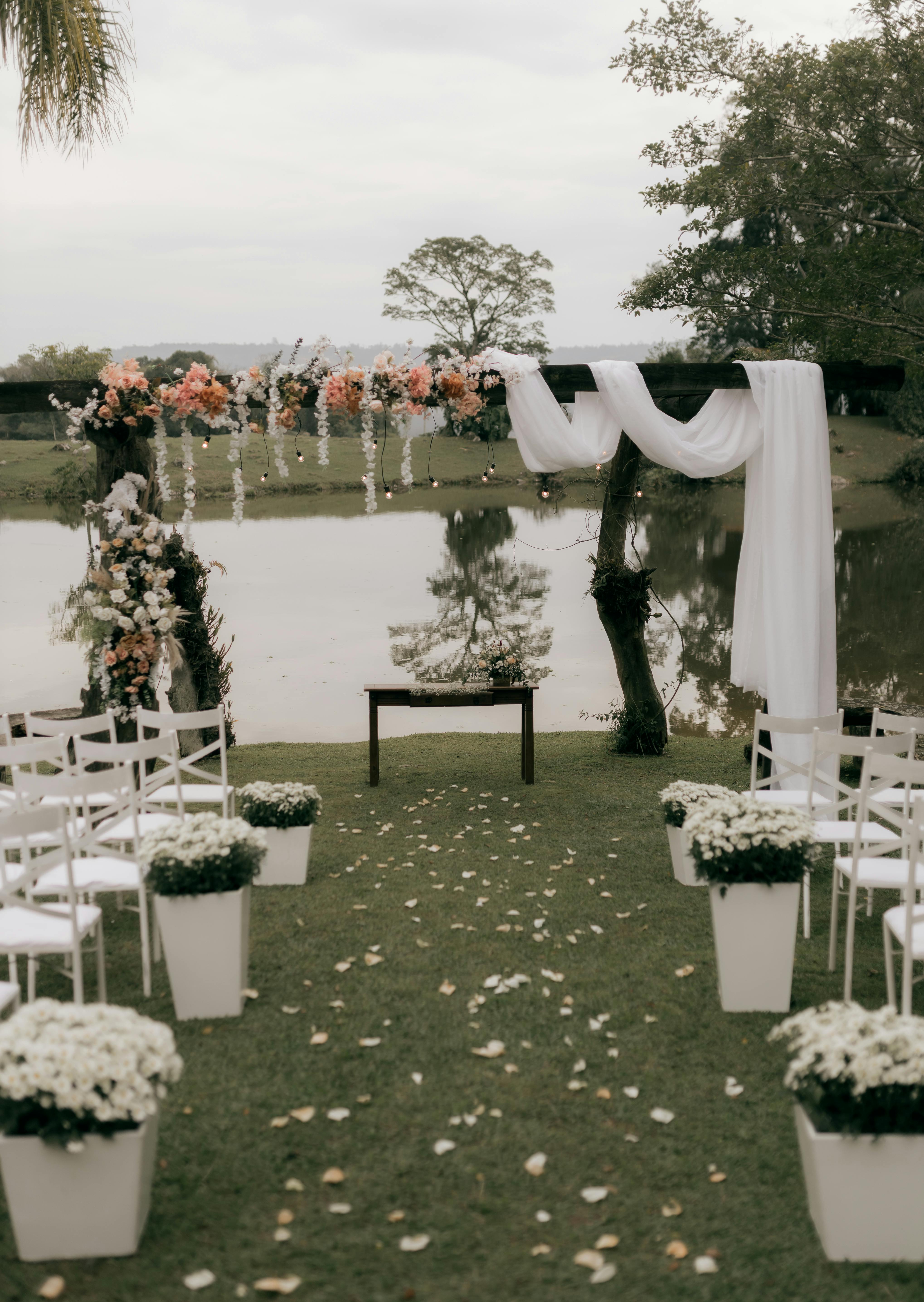 Beautiful floral wedding arch setup by a serene lakeside, ideal for outdoor ceremonies.