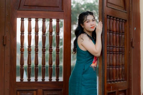 Free Stylish woman in a blue dress poses confidently by rustic wooden doors. Stock Photo