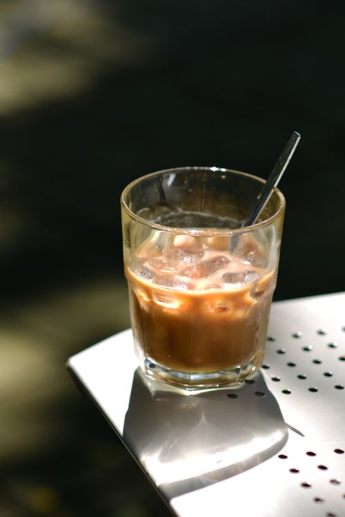Free Refreshing iced coffee with ice cubes on sunlit outdoor table for a perfect summer day. Stock Photo