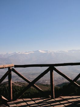 Breathtaking view from a wooden balcony overlooking snow-capped mountains near Skopje, North Macedonia.