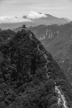 Black and white view of a pagoda atop a mountainous landscape, offering a serene and timeless perspective.