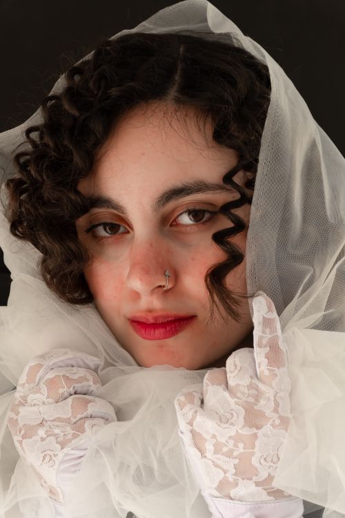 Free Close-up portrait of a woman with curly hair in a lace veil and gloves. Stock Photo