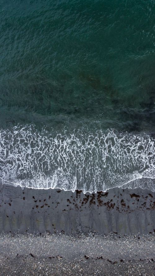 Free Stunning aerial view of the Scottish coastline with crashing waves and pebble beach. Stock Photo