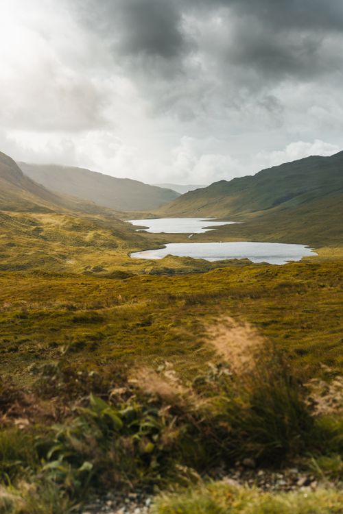 Free Breathtaking landscape of the Scottish Highlands overlooking serene lochs under a dramatic sky. Stock Photo