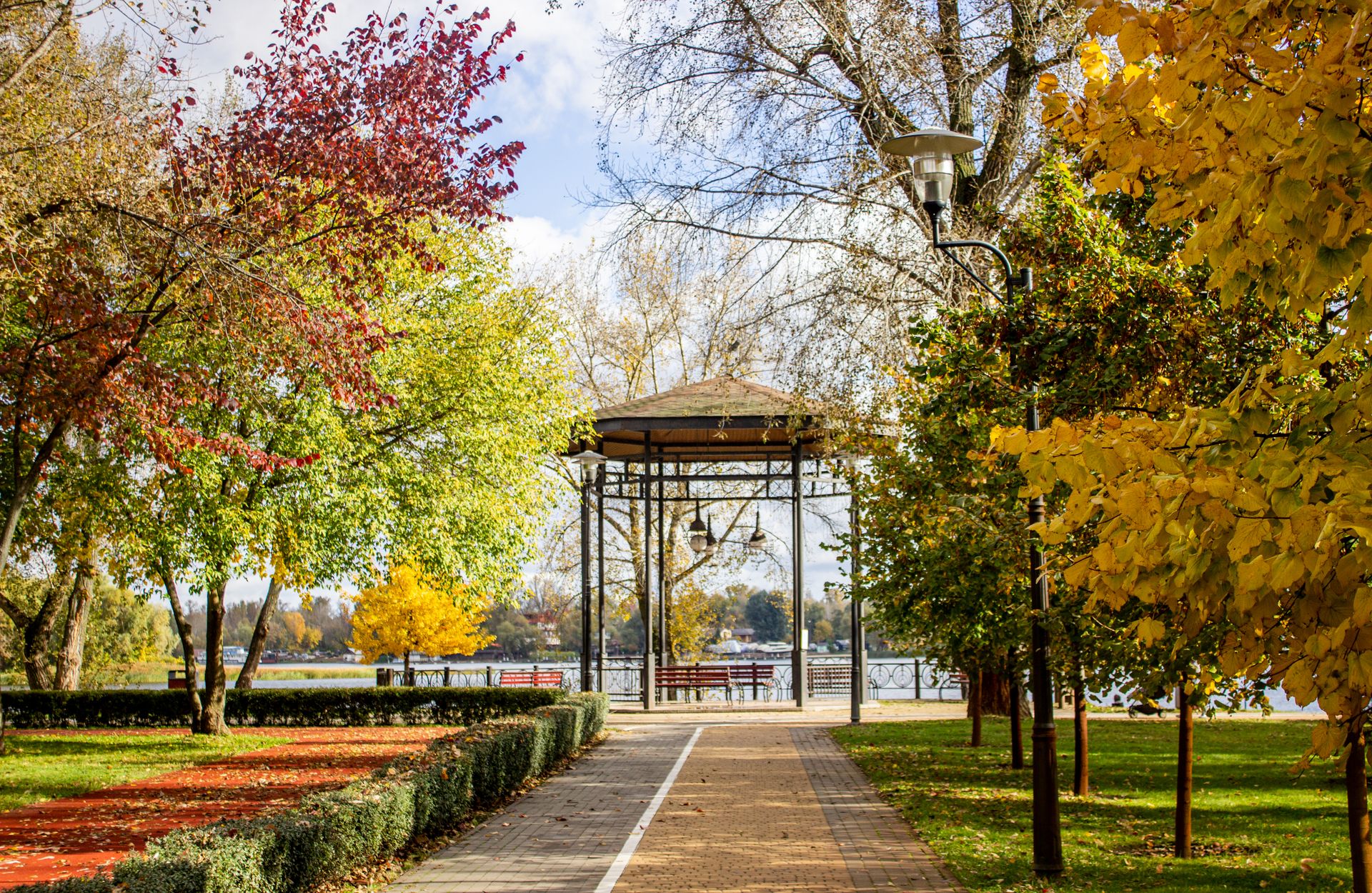 Serene autumn park scene with colorful foliage, a gazebo by the lake, and vibrant fall colors.