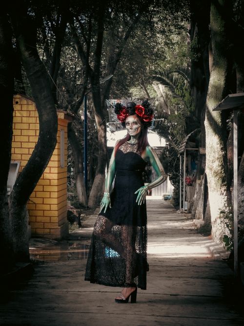 Free A woman dressed as Catrina poses elegantly in a cemetery for Día de Muertos. Stock Photo