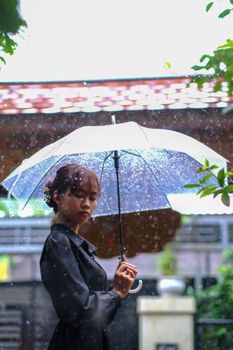 A serene moment captured of a woman with an umbrella in the rain in Hue, Vietnam.