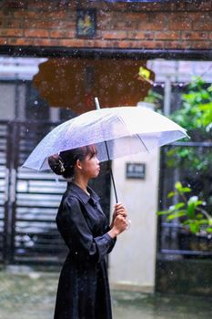A woman holding an umbrella on a rainy day in Hue, Vietnam, reflecting tranquility.
