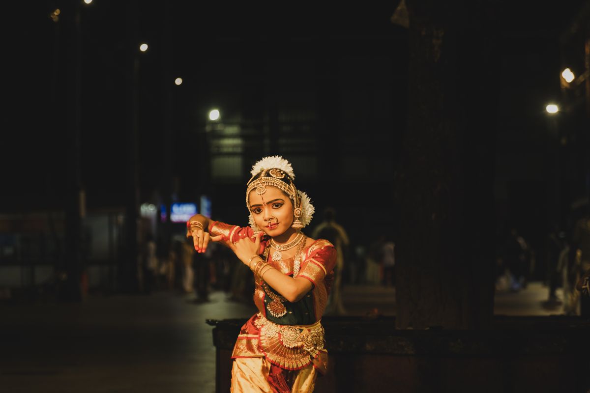 A Bharatanatyam dancer posing gracefully in traditional costume during an evening performance